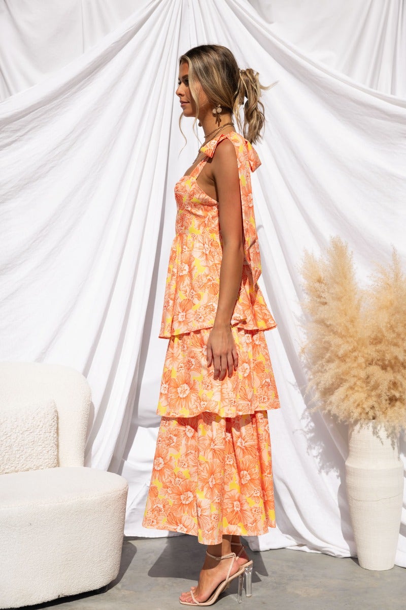 Connali Maxi Dress in floral print, featuring adjustable tie straps and tiered design, styled with a modern aesthetic.