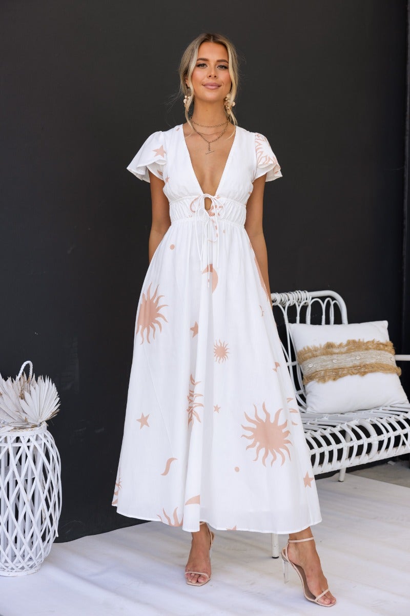 Model wearing Milene Maxi Dress, a cotton blend dress with tie detail, V-neckline, and sun print.