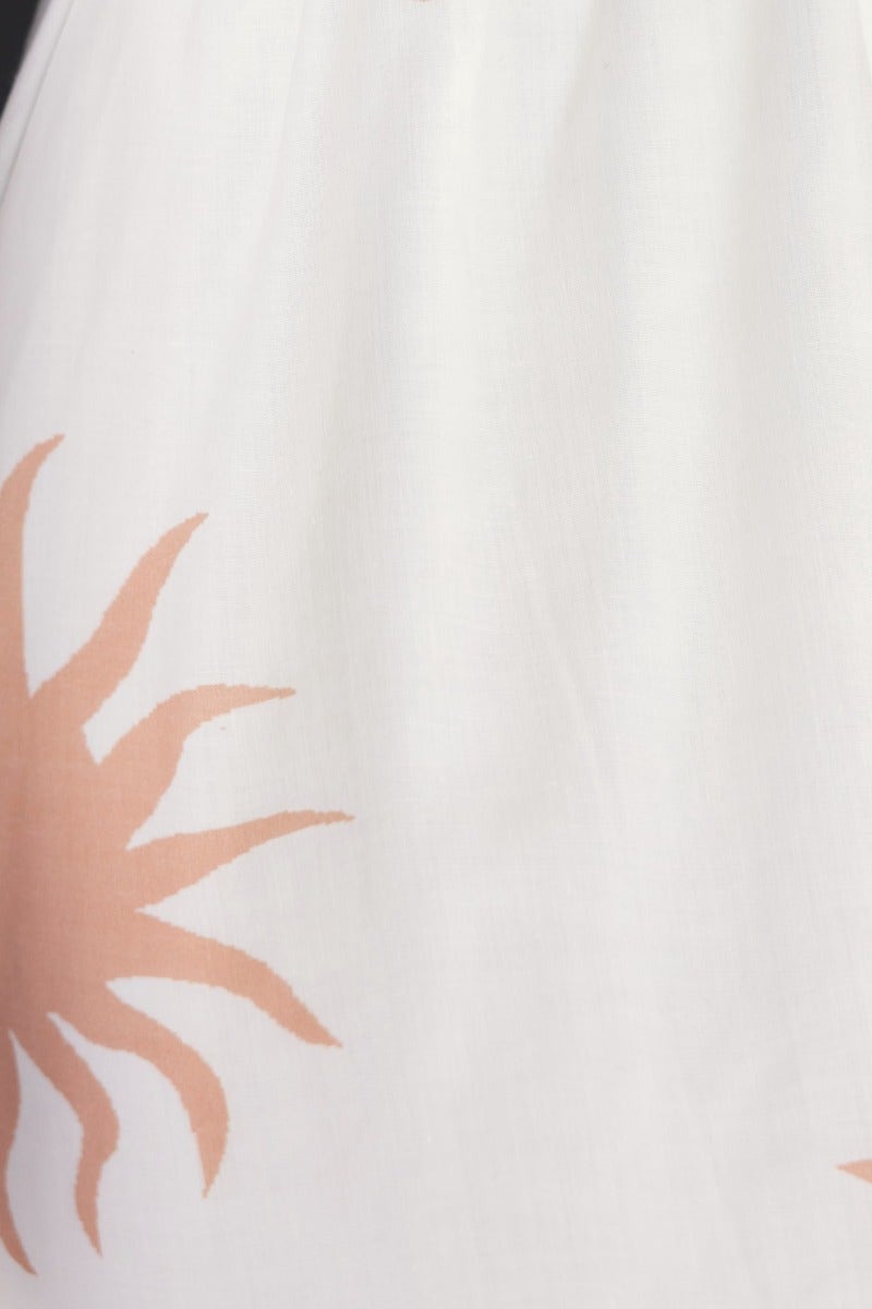 Close-up view of white cotton blend fabric with peach sun print design, featured on a Milene Maxi Dress.