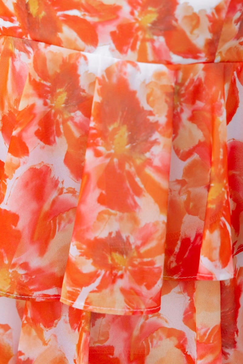 Close-up of floral print fabric in vibrant orange and white, showcasing layered design of the Koami Dress.
