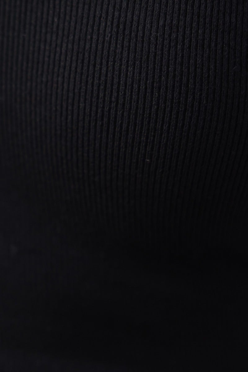 Close-up of the black ribbed fabric of the Unfoolish Maxi Dress, showcasing its stretchable material texture.