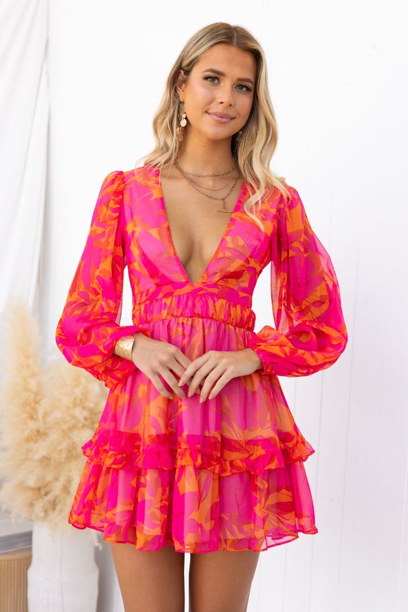 Floral print V-neck vanity dress in pink with elastic sleeves and layered skirt, worn by a model.