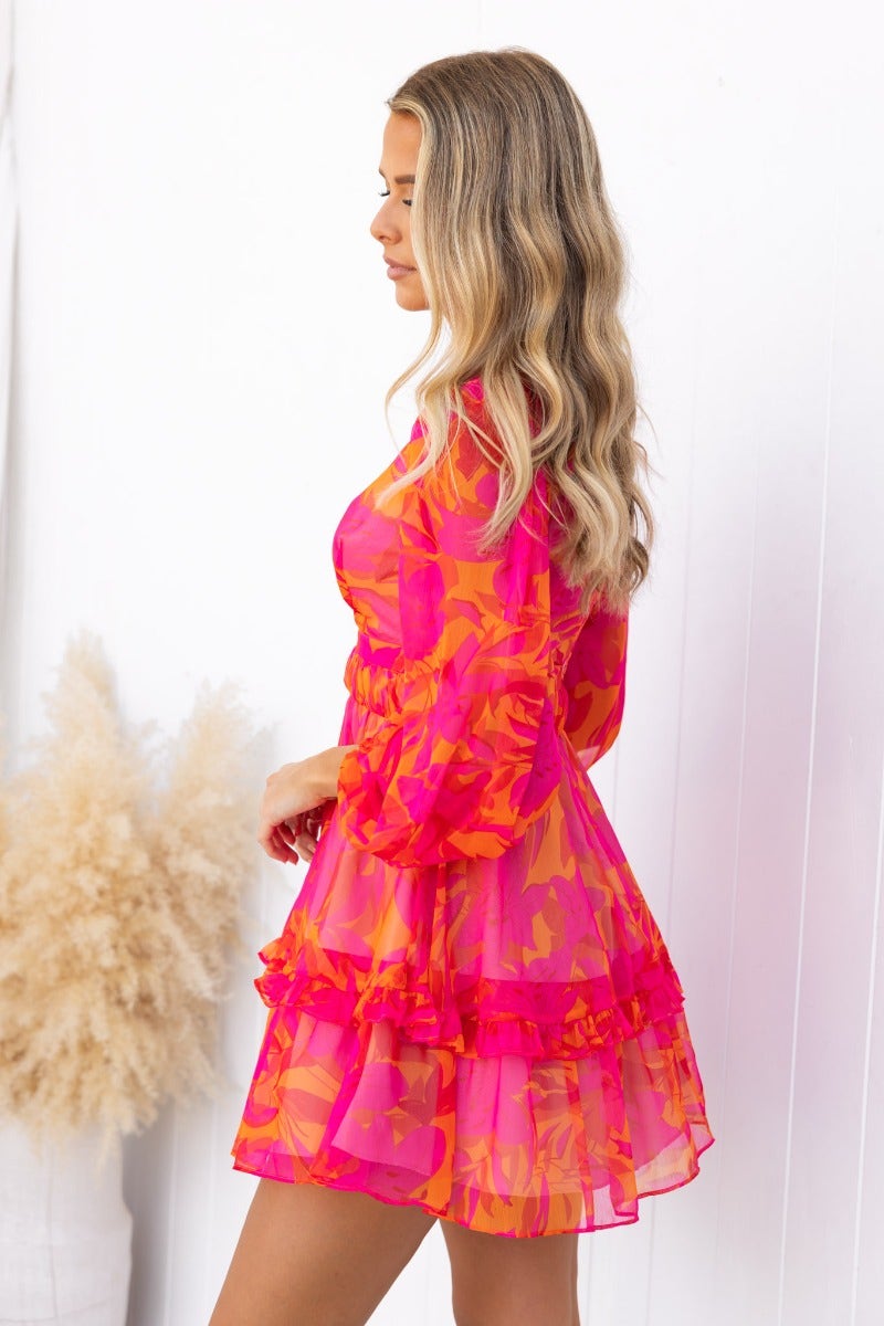 Floral print vanity dress with V-neckline and ruffled hem, perfect for summer outings, modeled in pink hues.