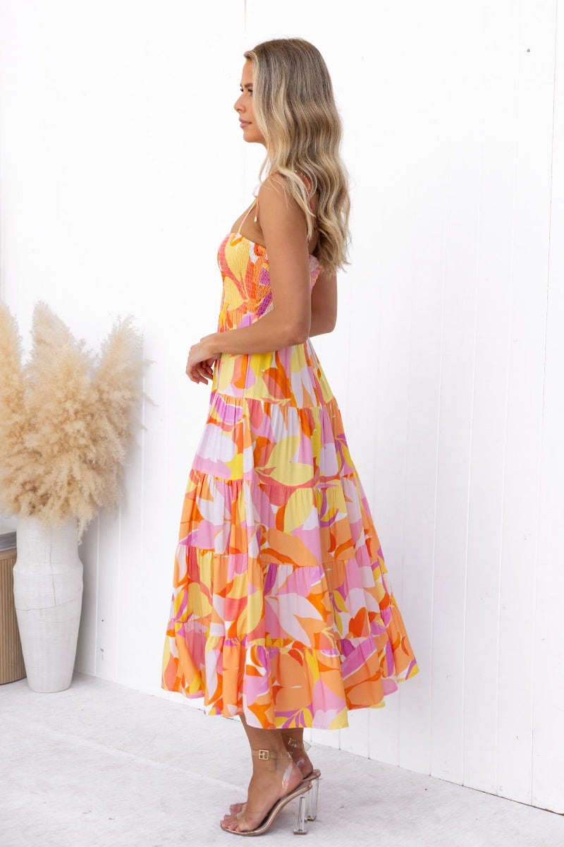 Model wearing multicolored Island Cruise Midi Dress with adjustable tie straps and elastic bodice.