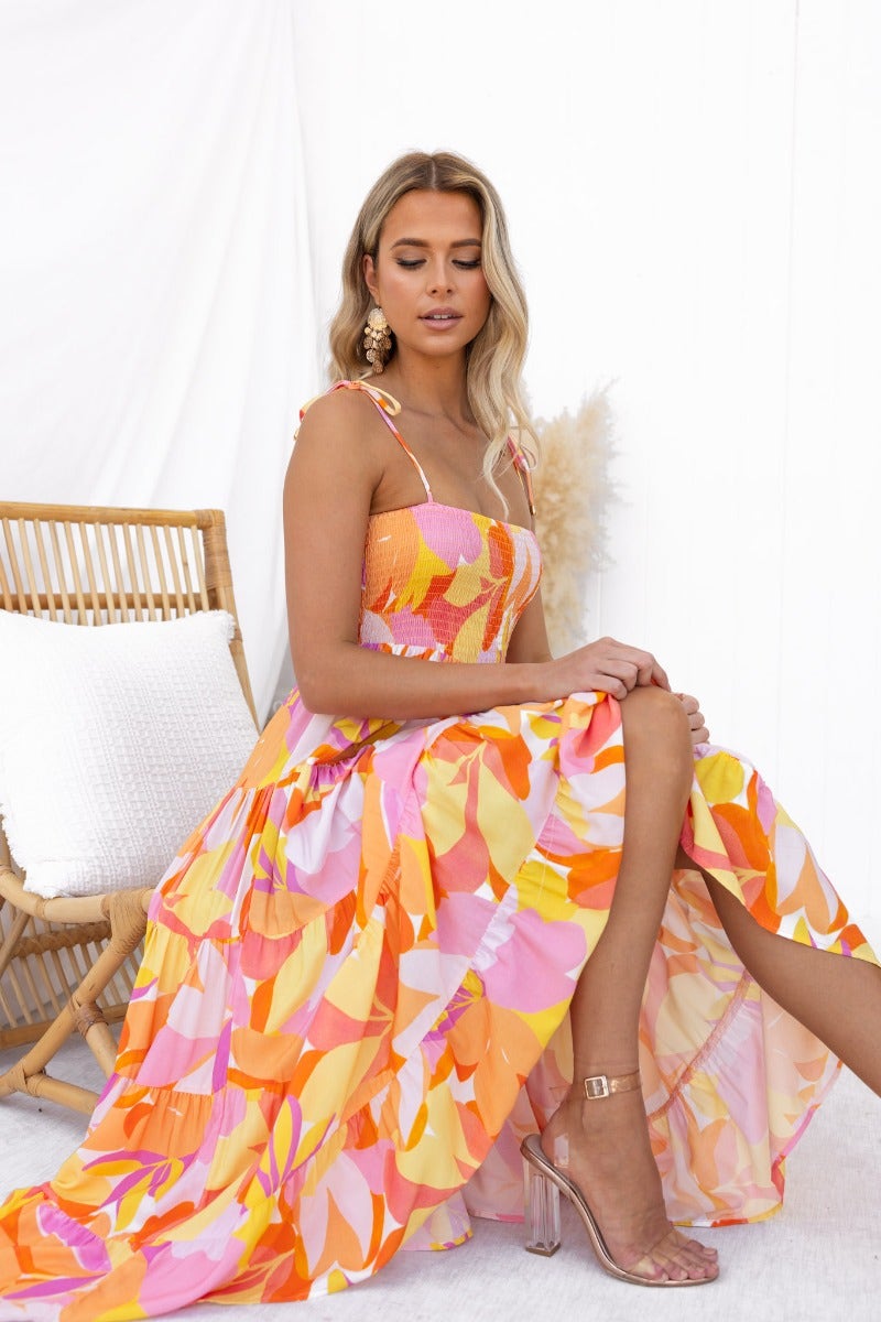 Model wearing the Island Cruise Midi Dress with vibrant colors and adjustable tie straps, showcasing a trendy summer look.