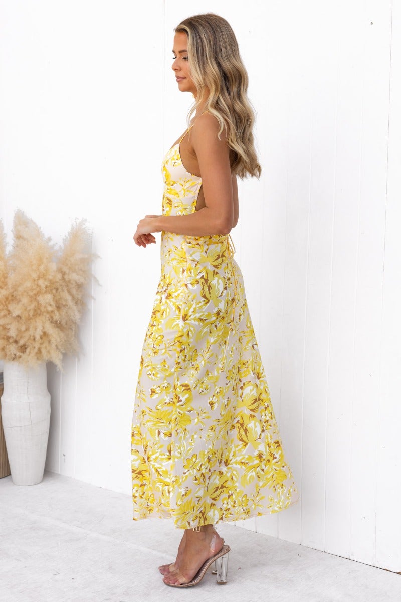 Side view of a woman in a floral print Ambra Maxi Dress with adjustable tie straps and draping material.