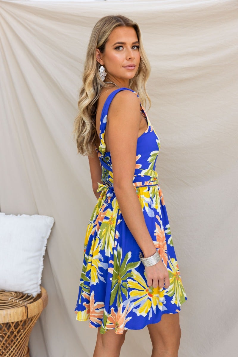 Floral print Haiti dress with adjustable straps, square neckline, and pockets, styled on a model.