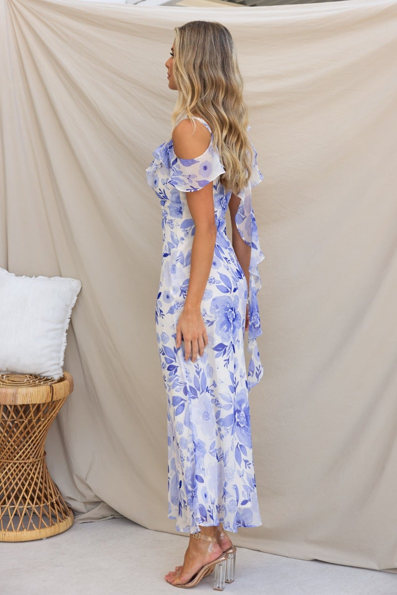 Model wearing Janelle Maxi Dress with floral print and ruffle detail, showcased in a side view against a neutral backdrop.