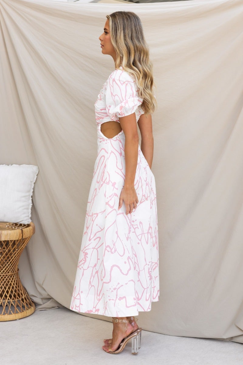 Side view of Jaida Maxi Dress featuring cut-out waist and elastic sleeves, styled with heels against a neutral background.