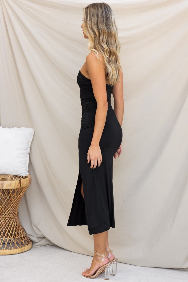Riri Midi Dress in black, showcasing strapless design, side view, high front split, and tie detail at bust.