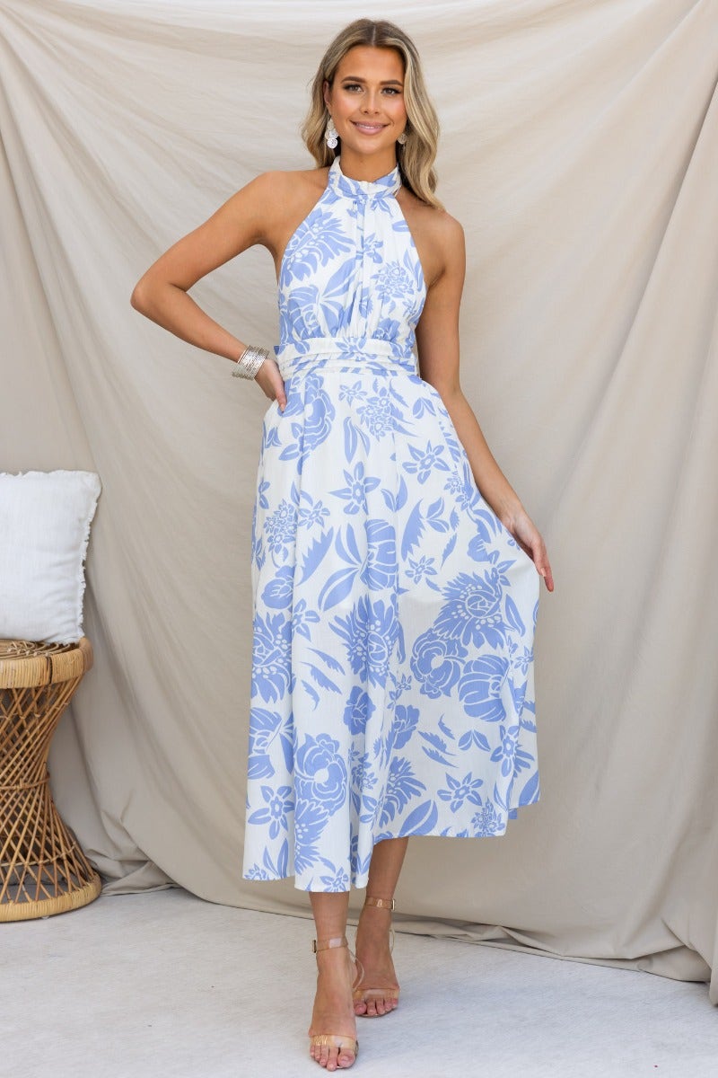 Model wearing Corio Midi Dress, a cotton halter neck dress with floral print and a fitted bodice, against a neutral backdrop.