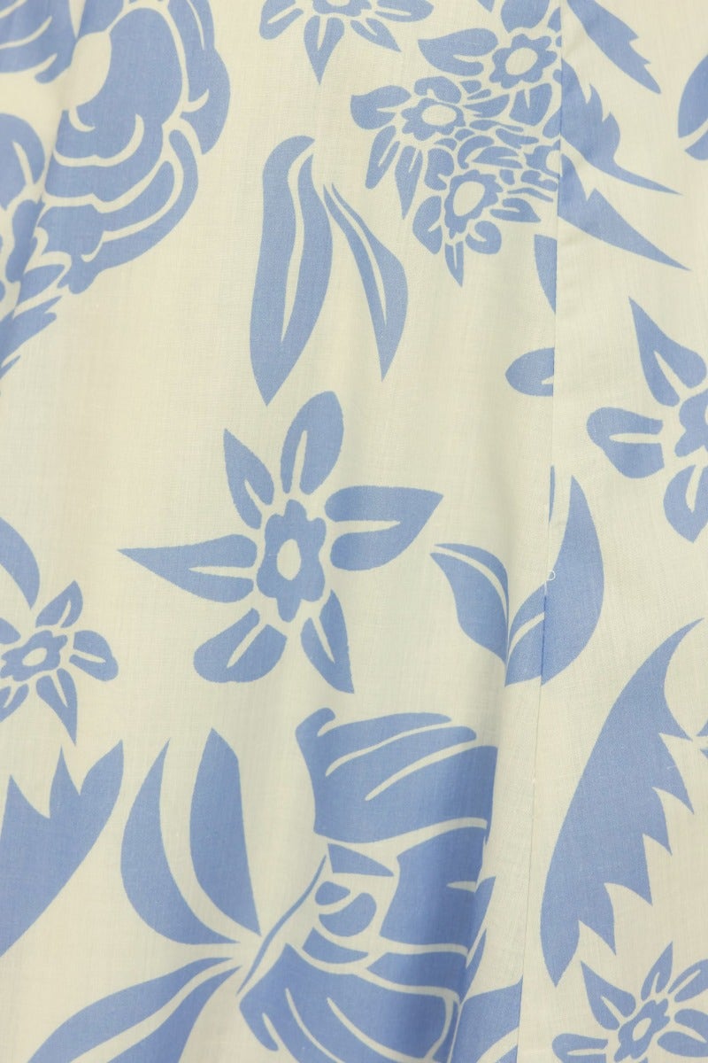 Close-up of floral pattern in light blue on a cream background, featuring leaves and blossoms design.