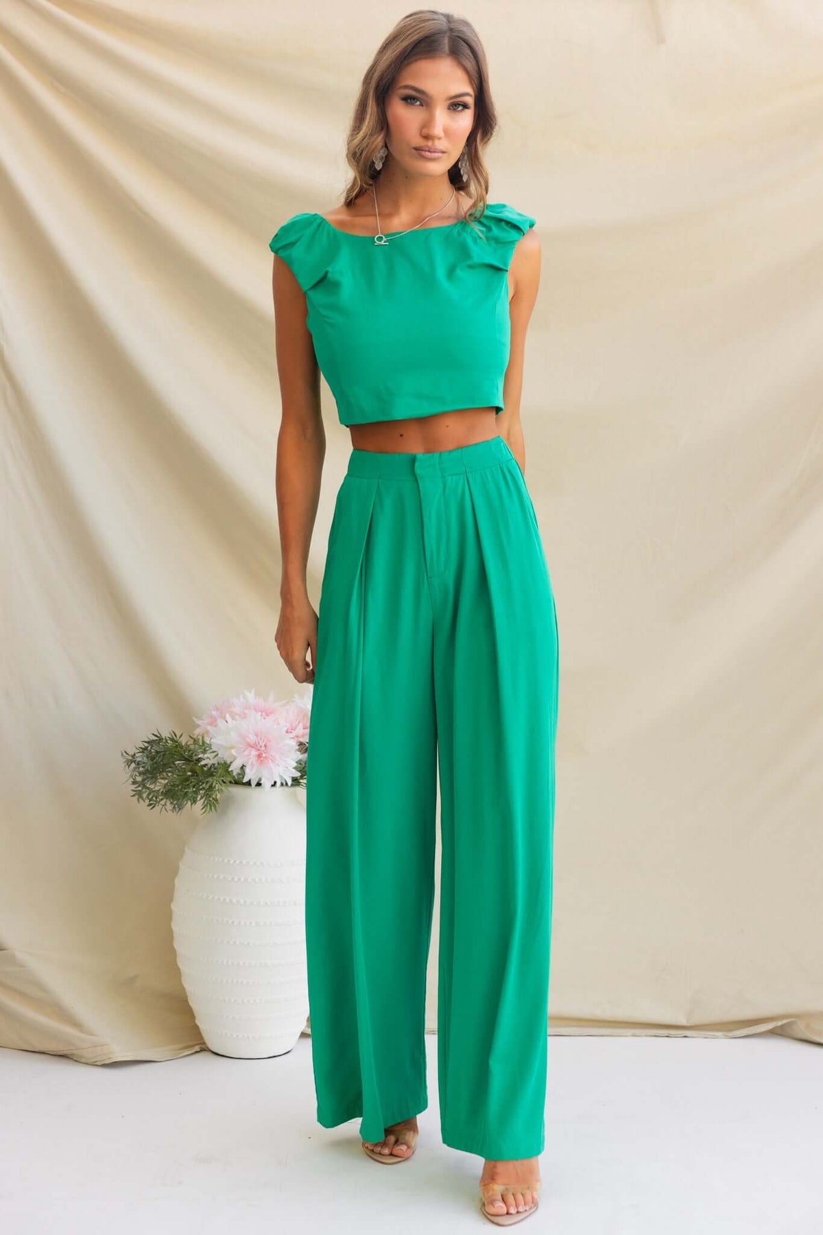 Model wearing a green cropped top with ruffles and matching wide-leg pants, styled against a neutral backdrop.
