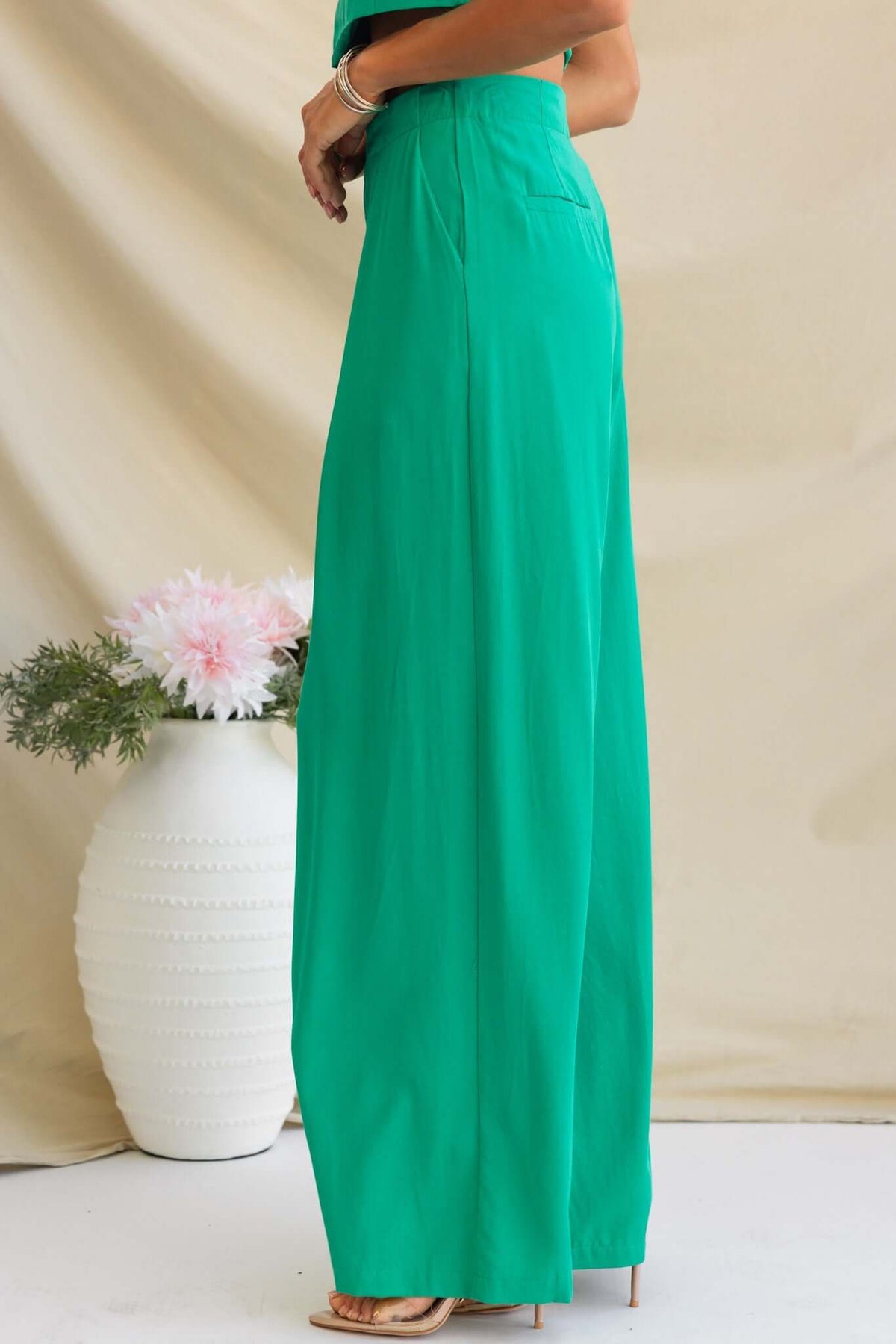 Green Erik pants featuring a mid-high waist fit and faux back pockets, styled for a chic look.