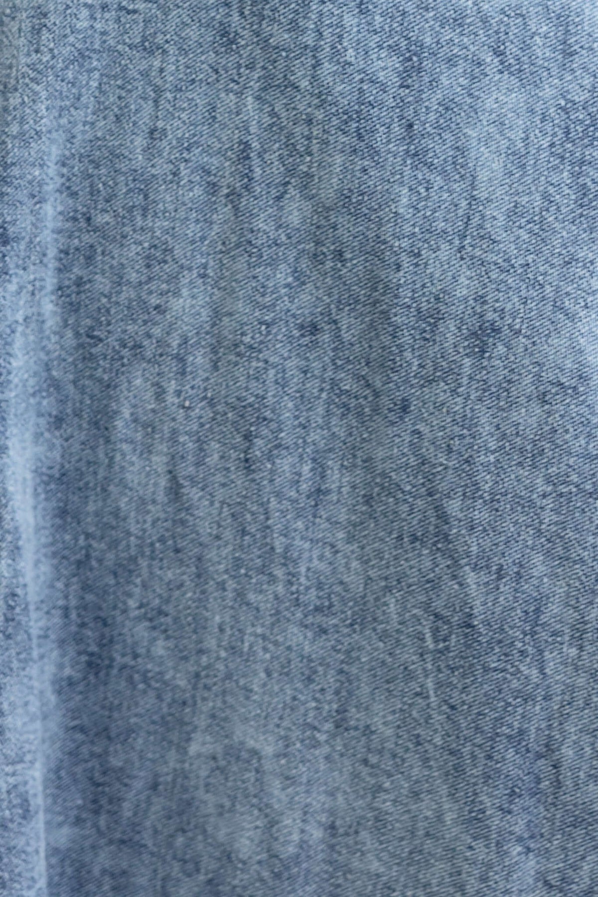 Close-up of denim fabric texture in light blue, showcasing the fibers and woven details.