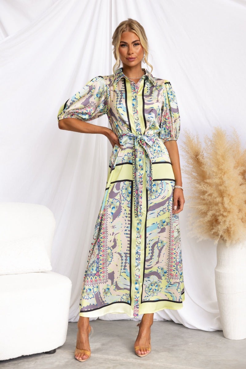 Nicosia maxi dress featuring an abstract print, button-up front, and removable tie, styled casually.