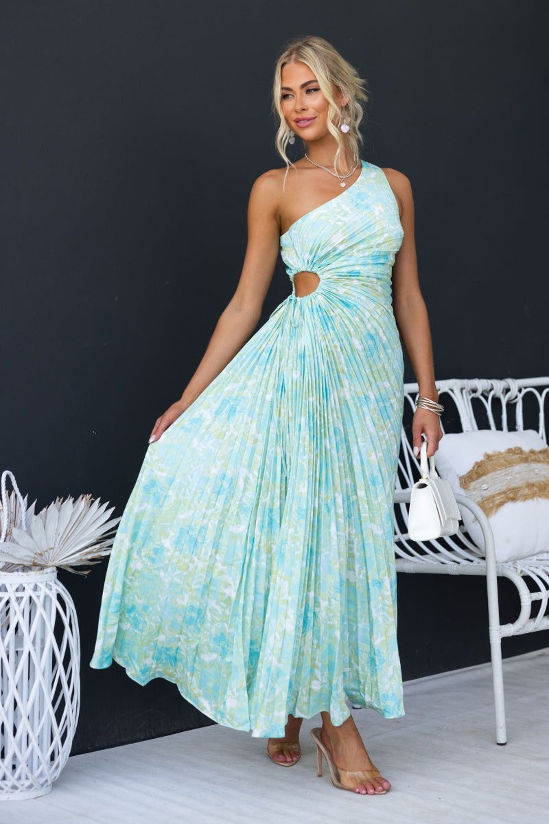 Ottile Maxi Dress featuring a floral print, one-shoulder neckline, cut-out waist, and pleated skirt in light blue.
