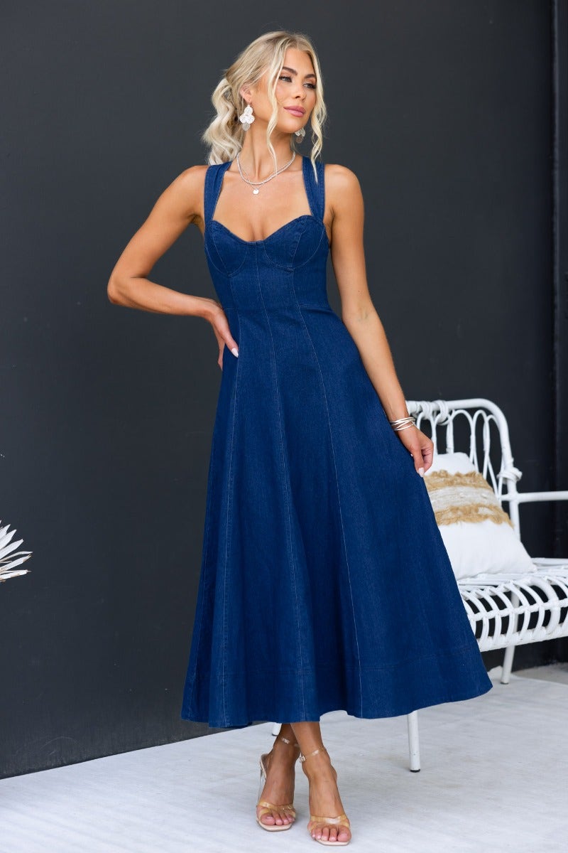 Woman wearing a dark navy Pallara denim midi dress with adjustable straps and a flattering fit.