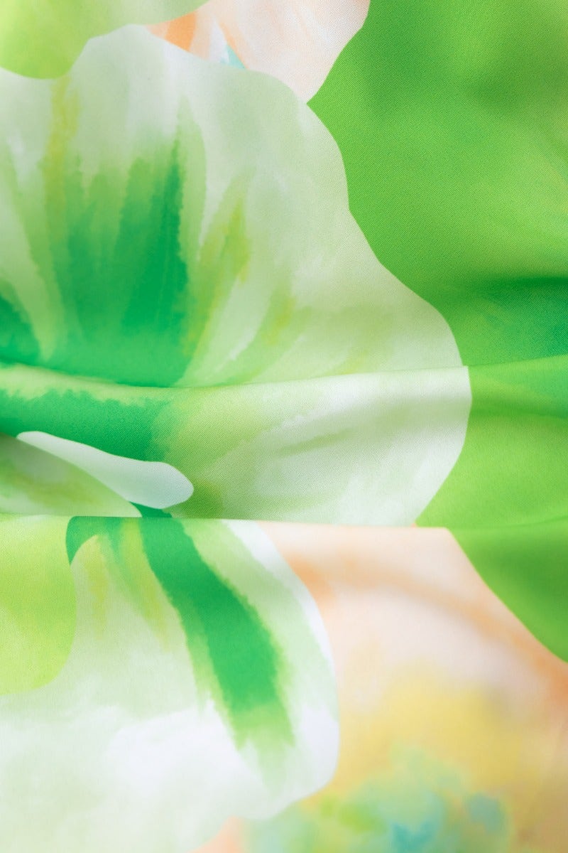Close-up of vibrant green and floral print fabric for the Qeilor Midi Dress, showcasing its delicate design and light material.