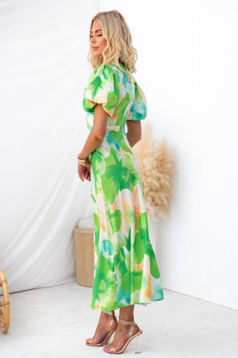 Model showcasing Qeilor Midi Dress with floral print, featuring a V-neckline and cut-out under bust in vibrant green.