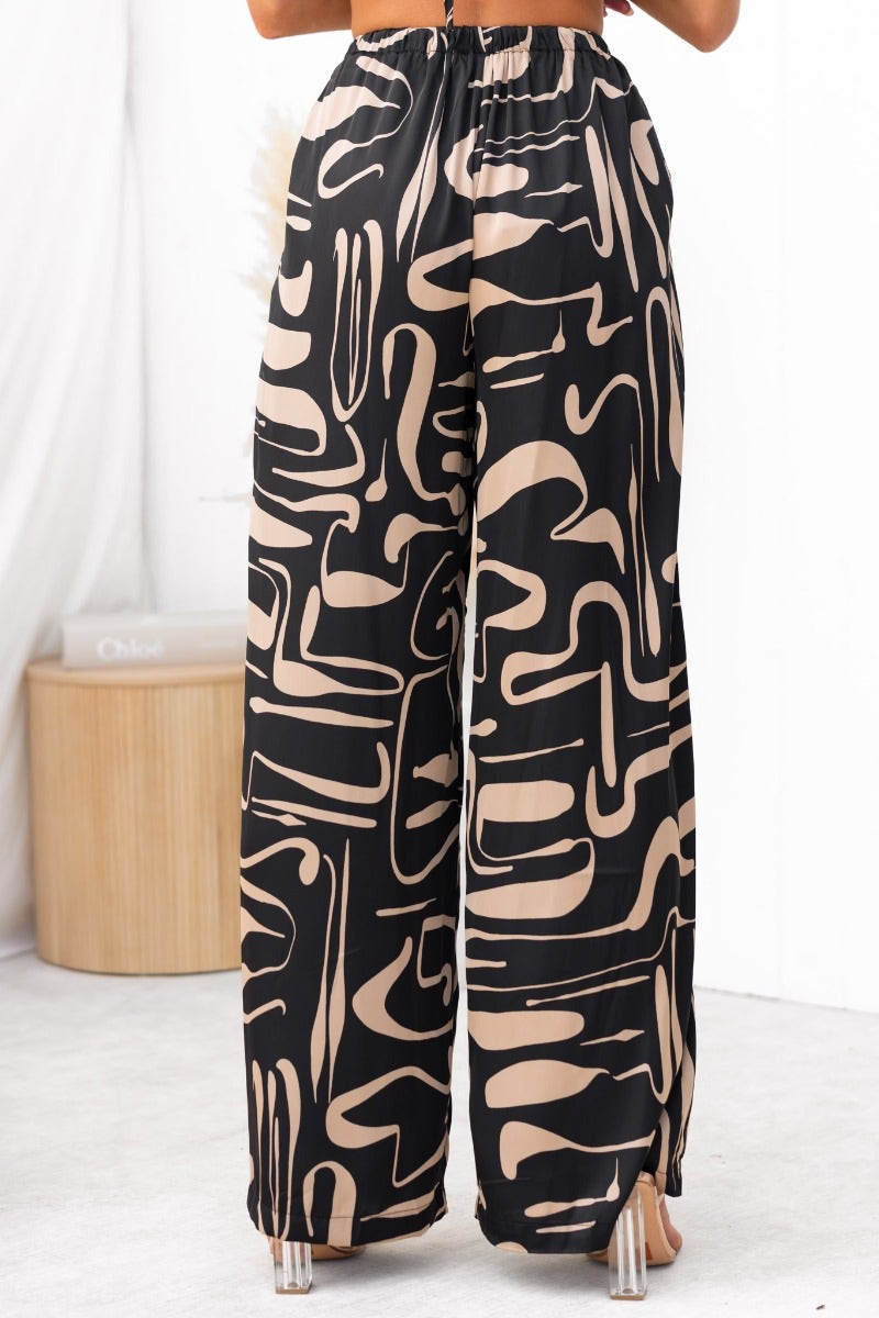 Stylish black and beige patterned pants featuring a mid-high waist and elastic waistband for comfort.