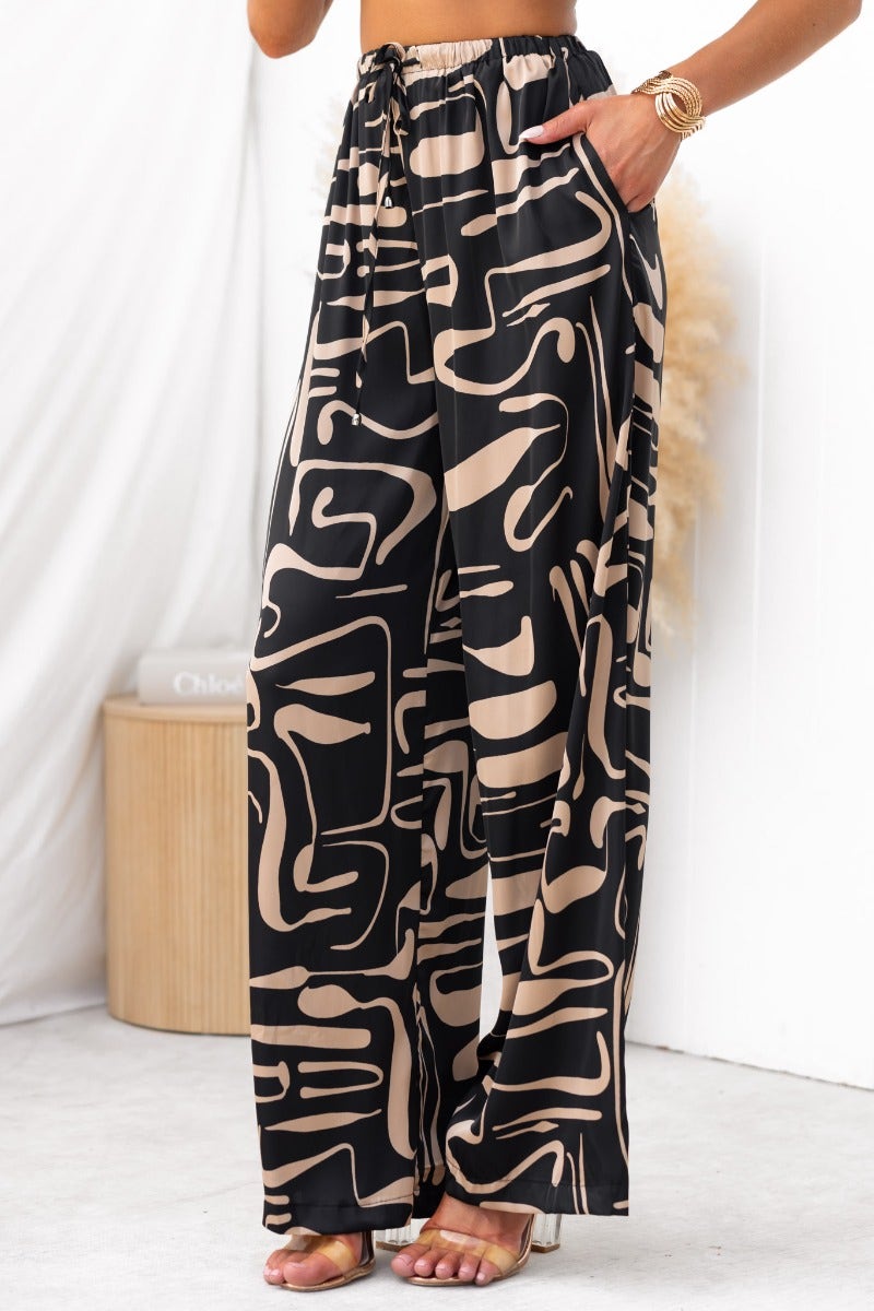 Stylish black and beige patterned wide-leg pants with elastic waistband and pockets, perfect for a chic outfit.