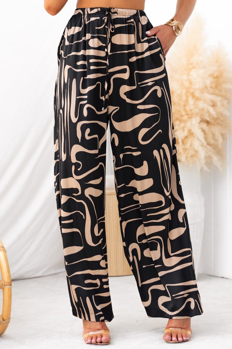 Stylish black and beige print pants featuring elastic waistband and mid-high waist fit, ideal for a chic look.