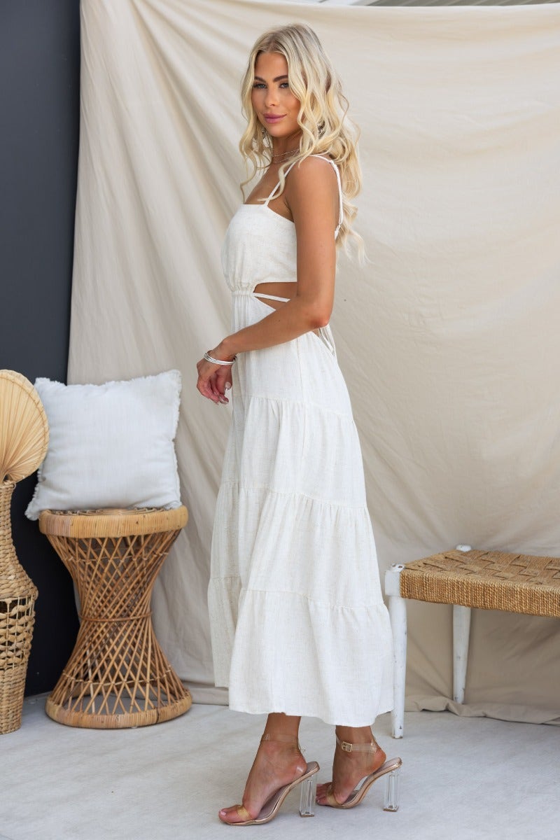 Elegant Brookman Midi Dress in white, featuring adjustable straps and cut-out design, styled with a natural backdrop.