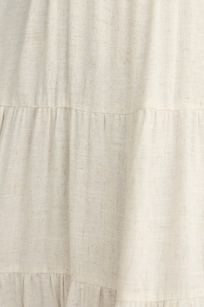 Close-up of the textured fabric of the Brookman Midi Dress in a neutral color, showcasing its linen look and subtle detailing.