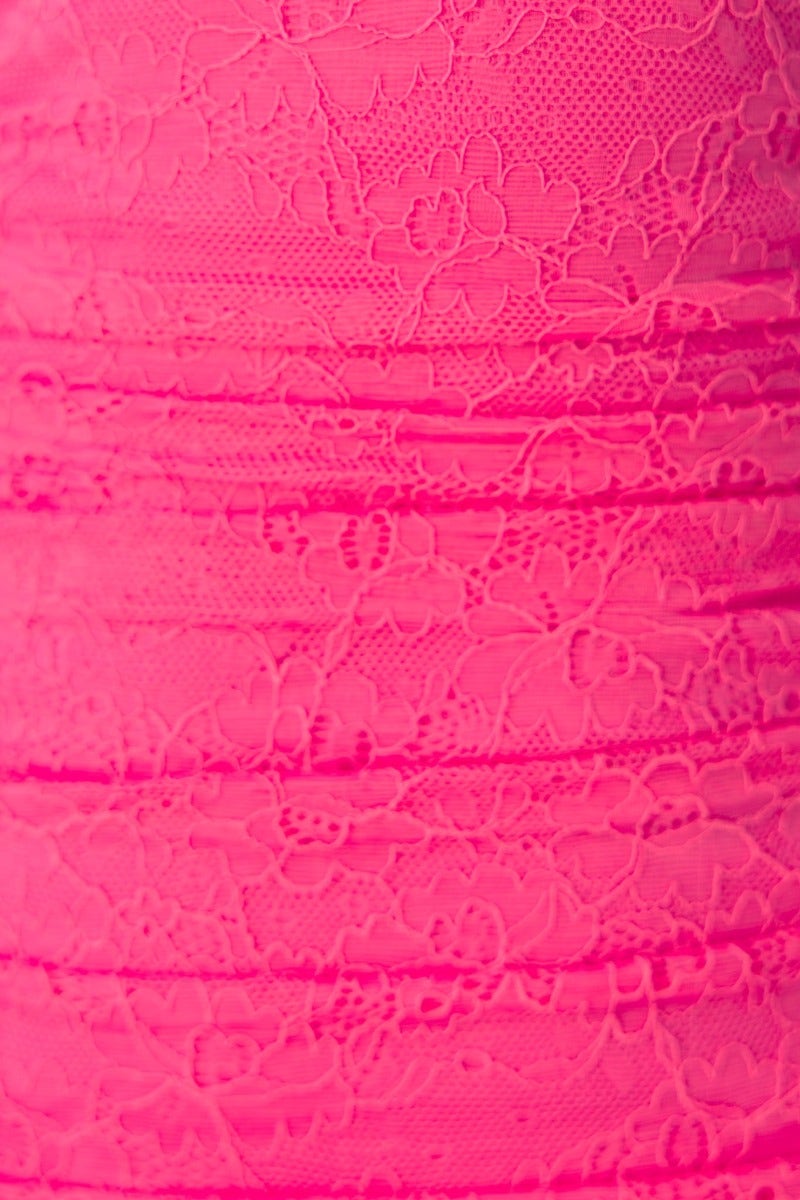 Close-up of a pink lace fabric with floral patterns, showcasing texture and intricate detailing.