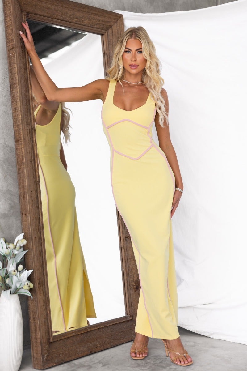 Yellow crepe maxi dress with a split at the back, styled with a mirror reflecting the outfit.