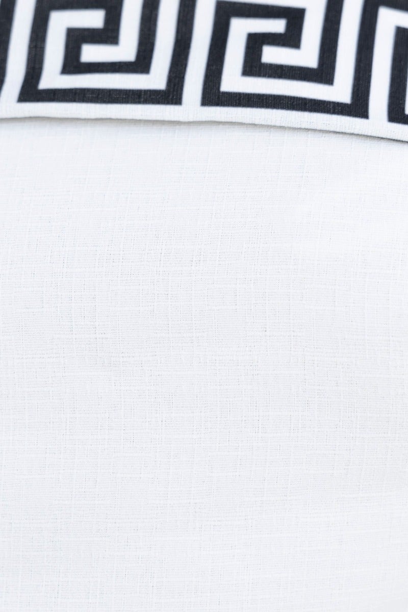 Close-up of a white fabric with a black Greek key pattern waistband.