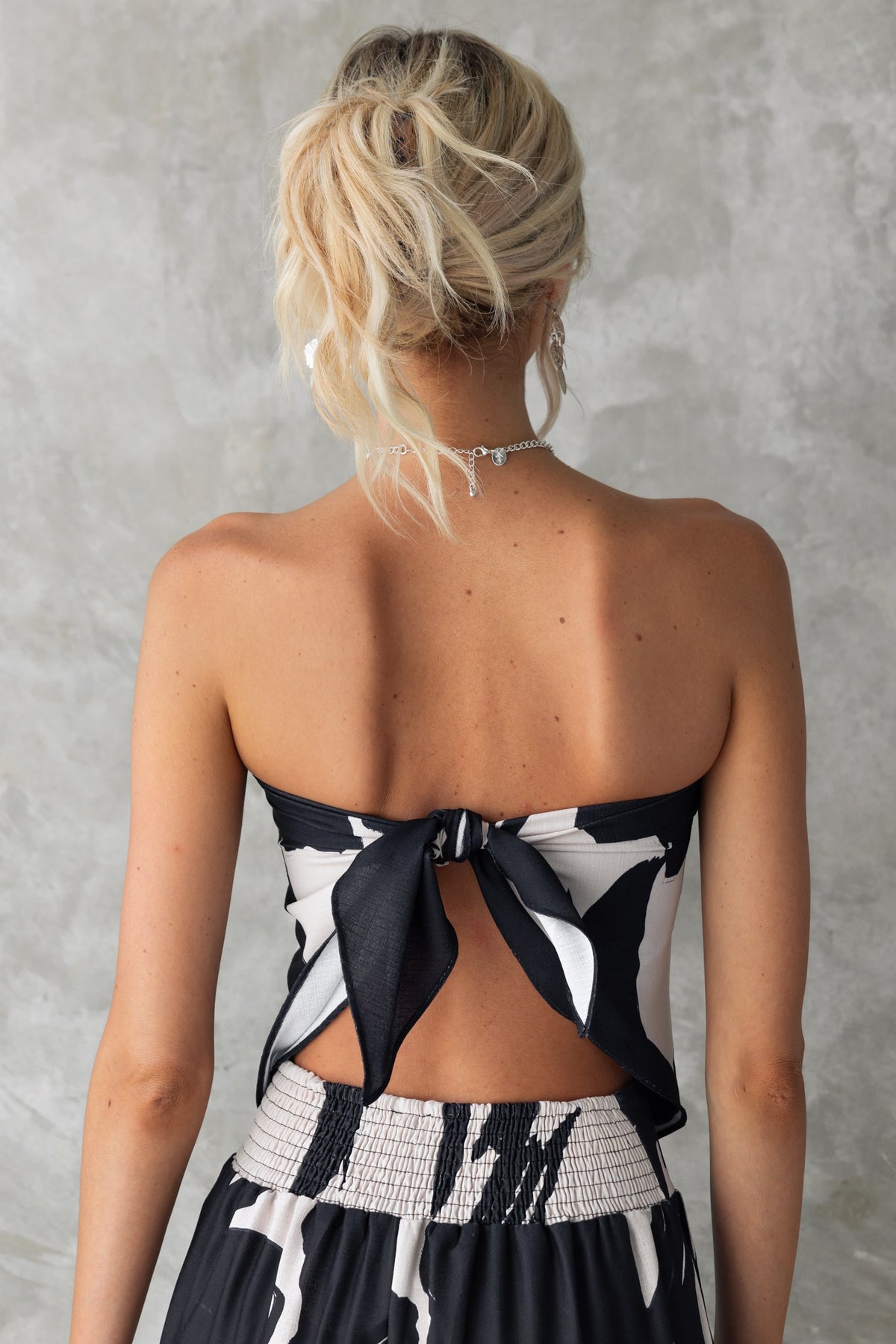 Back view of the Yanna Top featuring a black and white print and scarf tie design, highlighting its stylish fit.