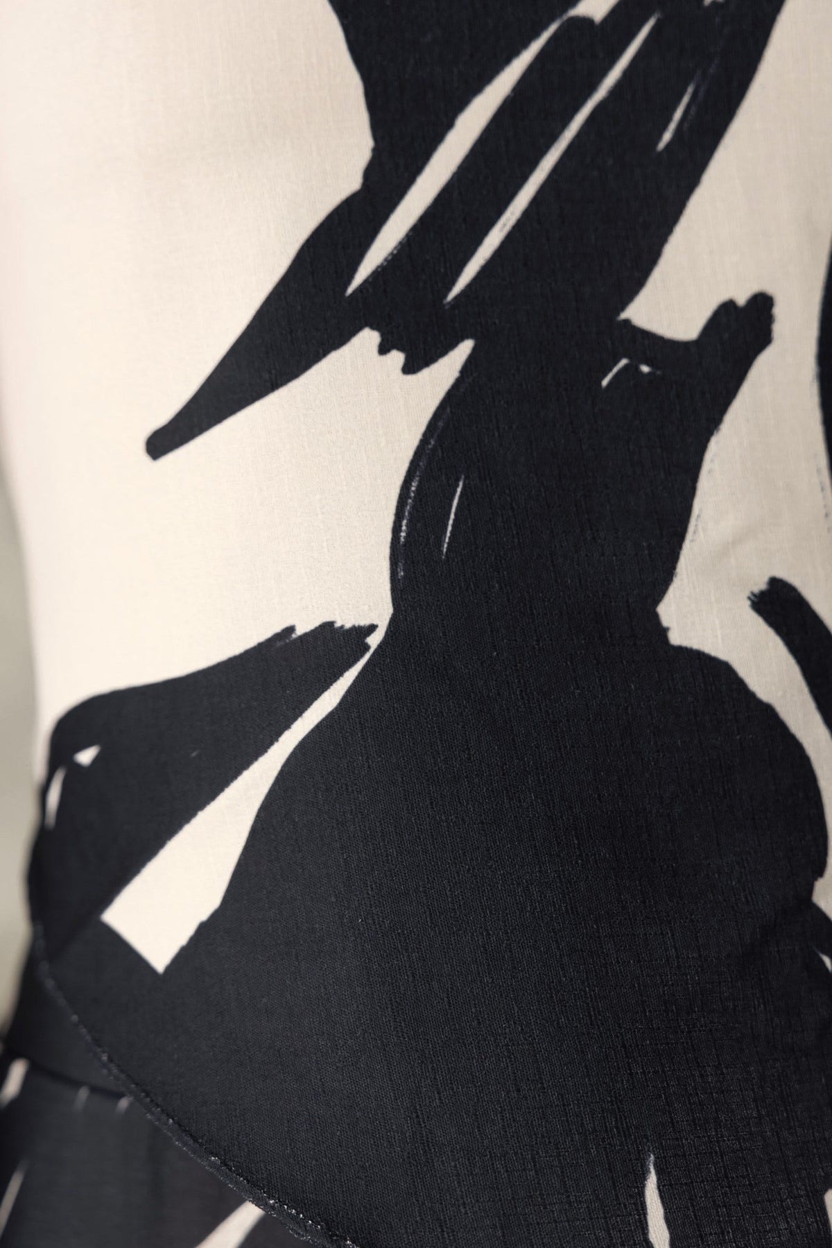 Close-up of Yanna Top featuring a black and white abstract print, showcasing fabric texture and scarf style design.