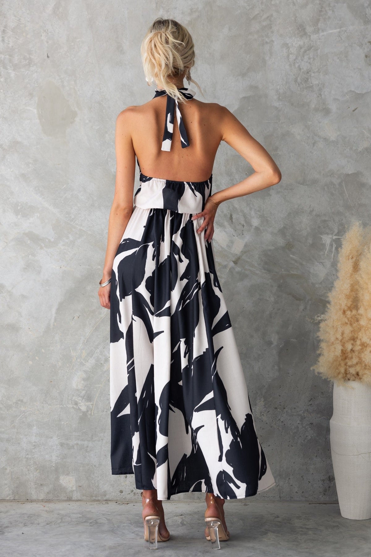 Back view of the Casilda Maxi Dress in a black and white print with adjustable tie neckline and flowy silhouette.