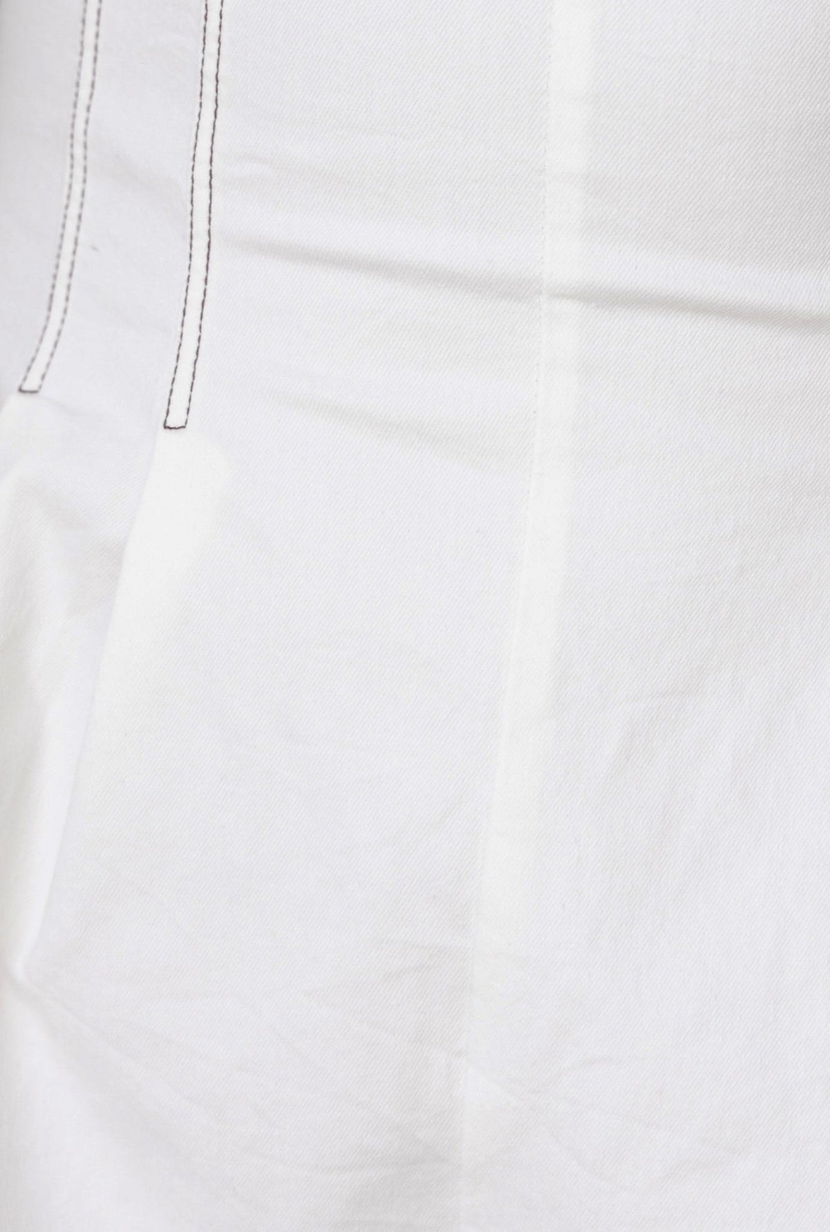 Close-up of soft white denim fabric with stitching details, showcasing texture and quality for fashion designs.