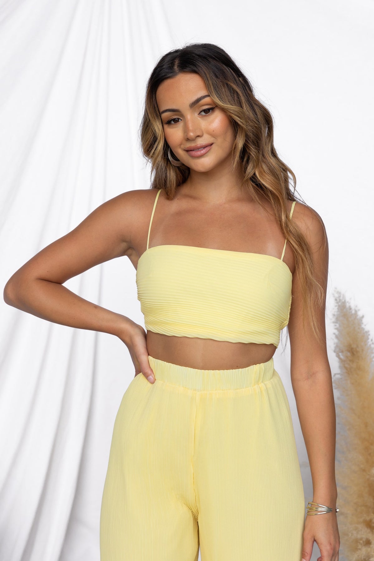 Woman wearing a yellow Elida Top with adjustable straps, styled with matching pants against a soft background.