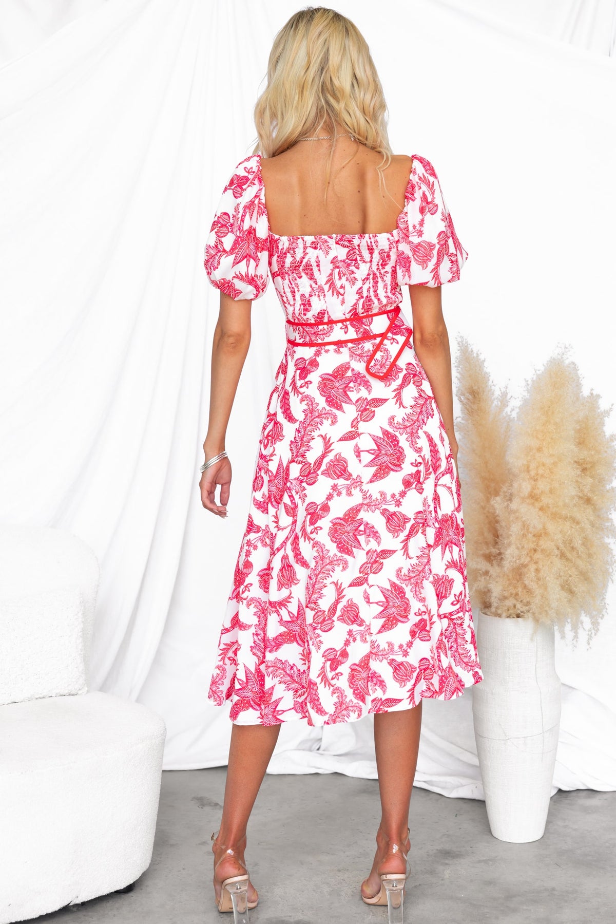 Back view of Omika Midi Dress featuring floral print, square neckline, and removable belt, styled with soft curls.