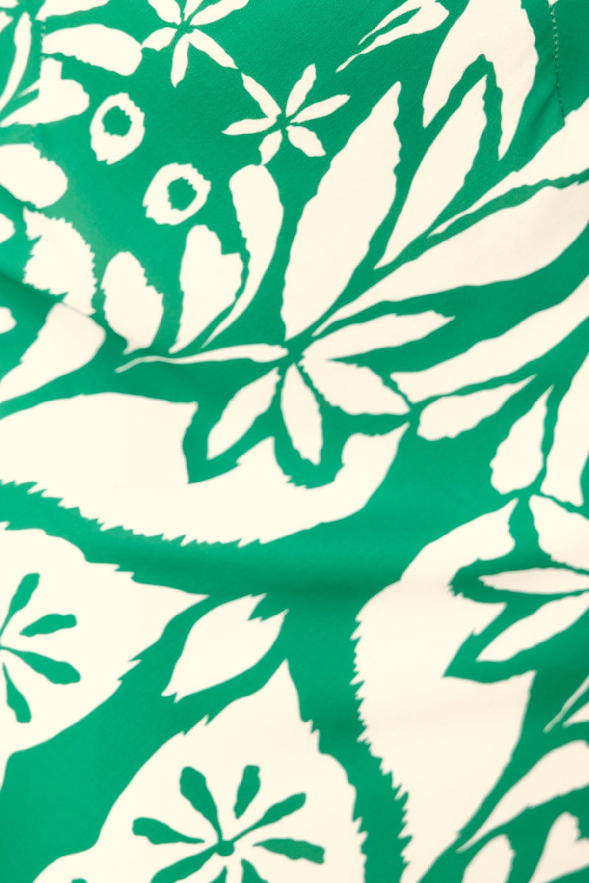 Close-up of a floral print in green and white, showcasing leaves and flowers, ideal for a stylish one-shoulder top.