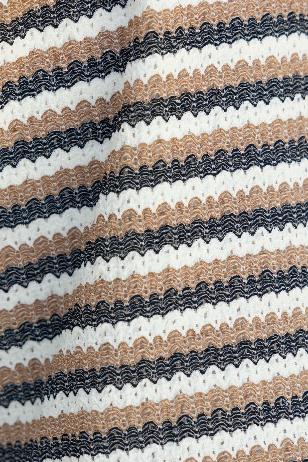 Textured fabric featuring alternating wavy stripes in beige, white, and black, ideal for stylish shorts.