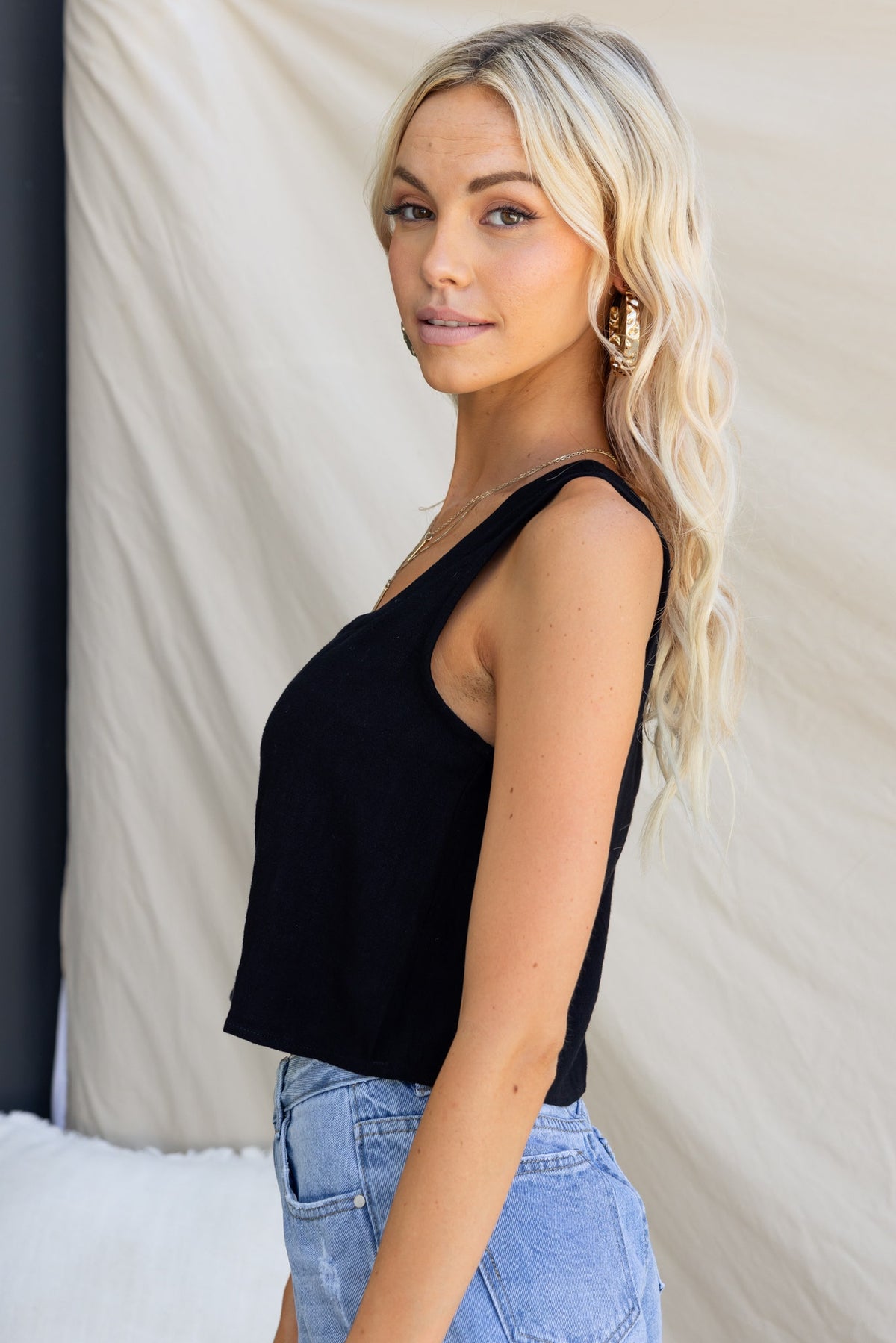 Model wearing a black Jaye Top with square neckline, faux buttons, styled with high-waisted shorts.