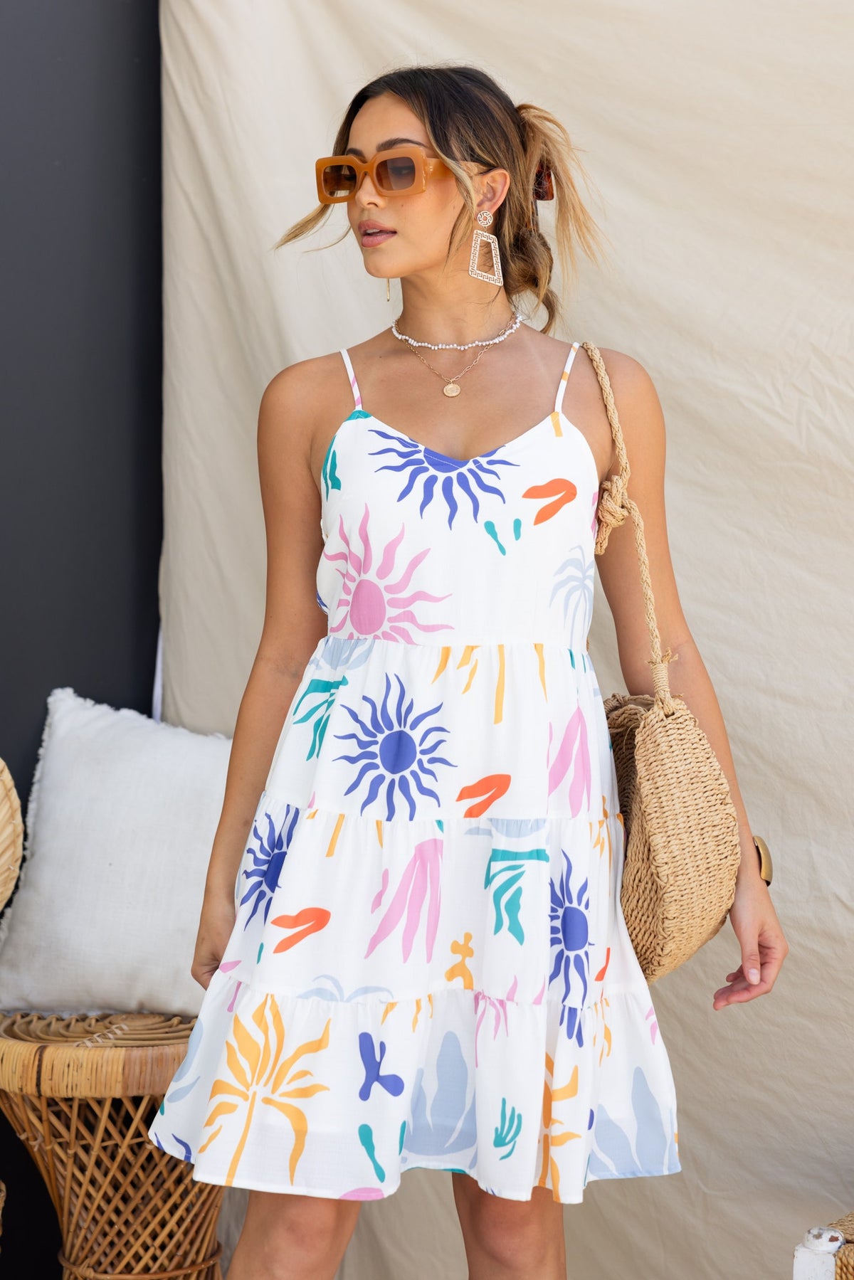 Model wearing the Romee Dress, an abstract print dress with adjustable straps and a playful floral design.