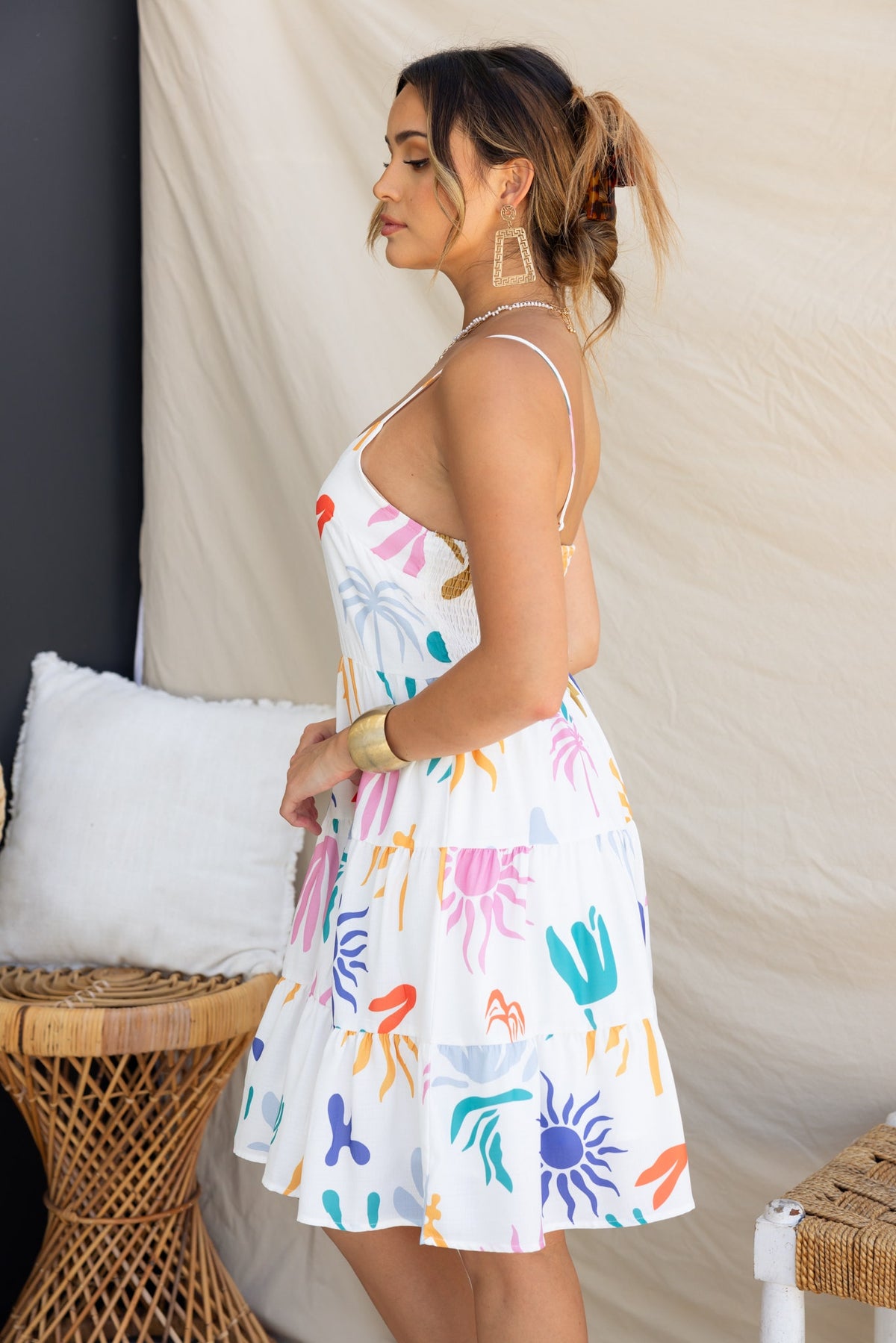 Romee Dress featuring abstract print, adjustable straps, and a flared skirt, modeled by a woman in a stylish setting.