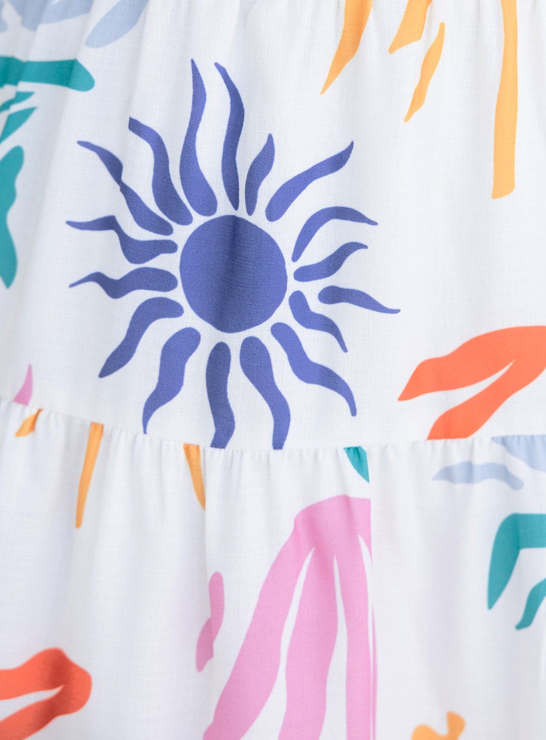 Close-up of abstract print featuring vibrant sun and floral designs on lightweight fabric of the Romee Dress.
