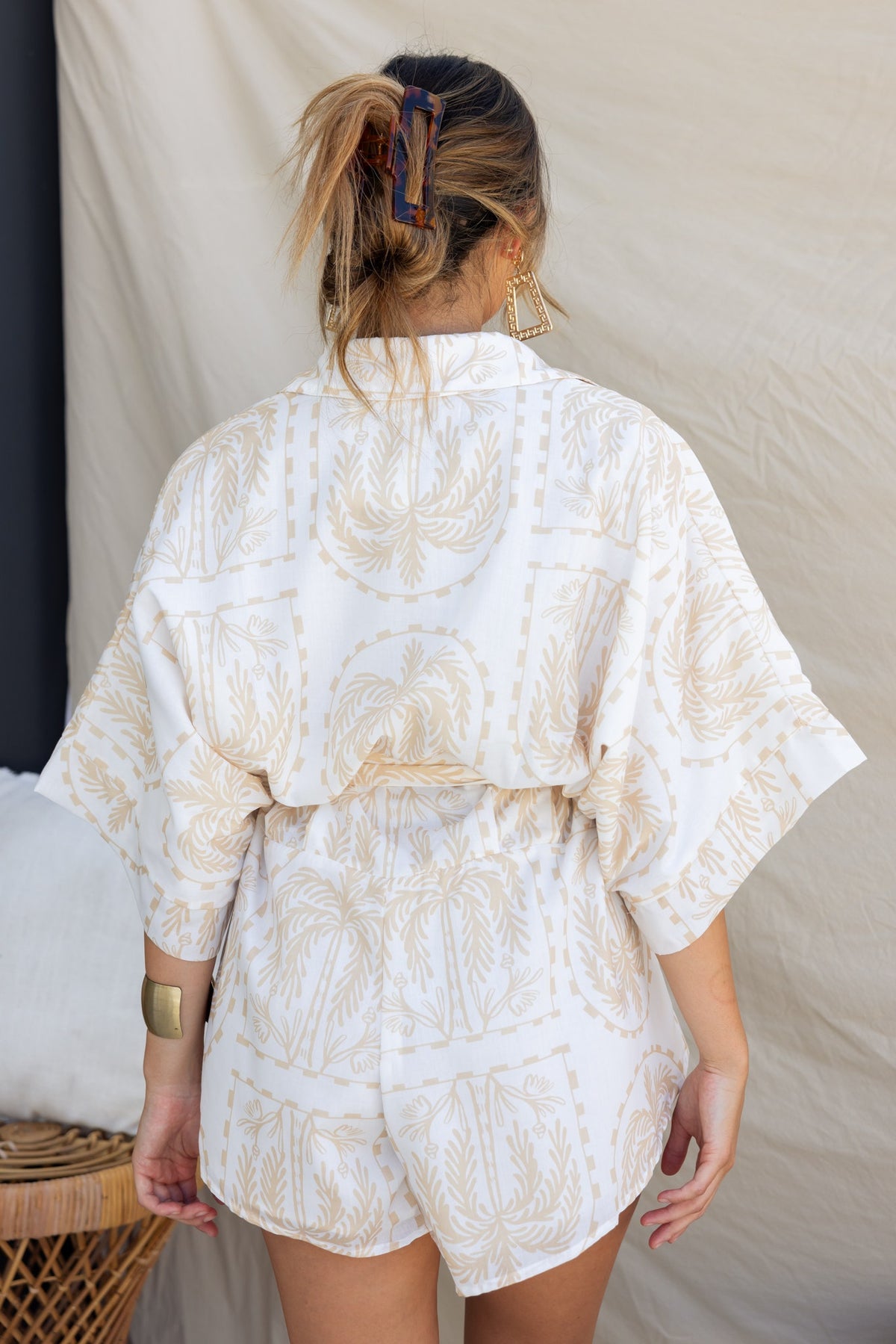 Back view of a woman in a stylish Alli playsuit with a collar and light cotton feel, featuring an oversized fit and unique print.