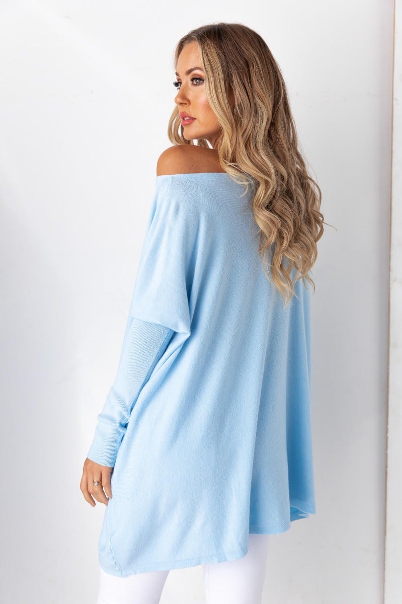 Oversized Bonnie Knit Top in light blue, featuring full-length sleeves and a relaxed fit, styled with white pants.