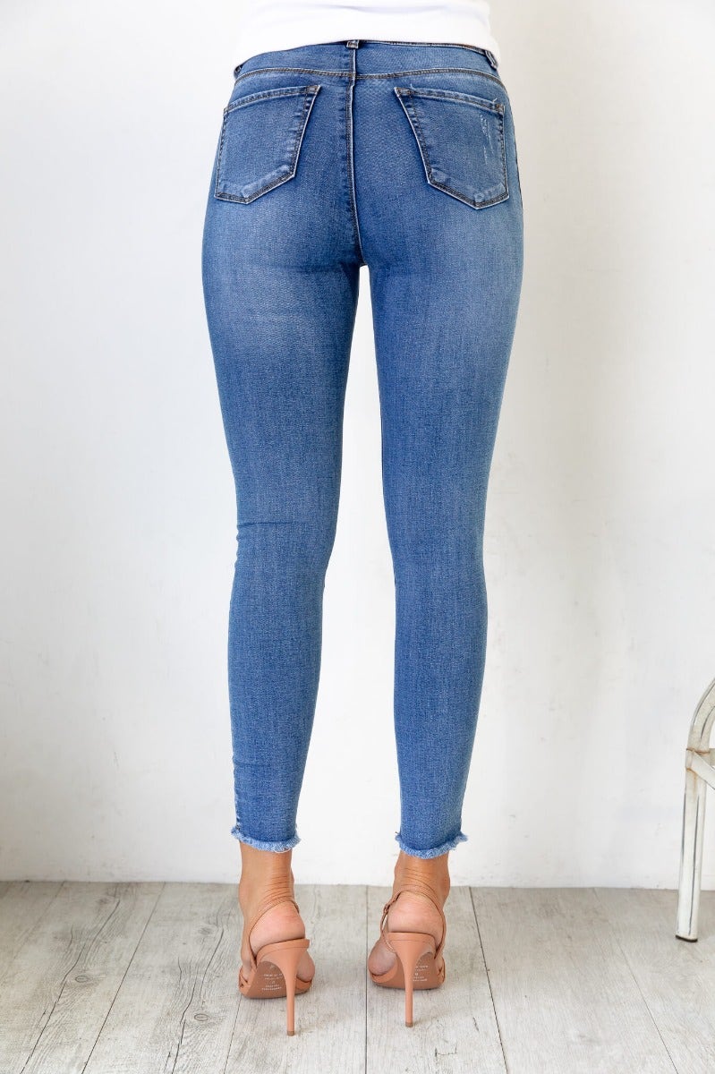 Back view of Juicebox Jeans showcasing mid waist fit, slight distressing, and raw hem details.