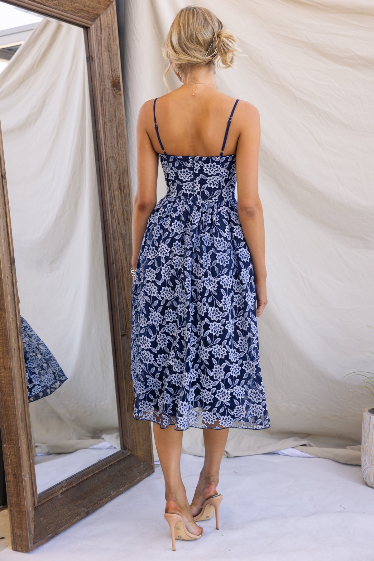 Back view of a model wearing a navy Ambient Midi Dress with lace and tulle details, adjustable straps, and a fitted silhouette.