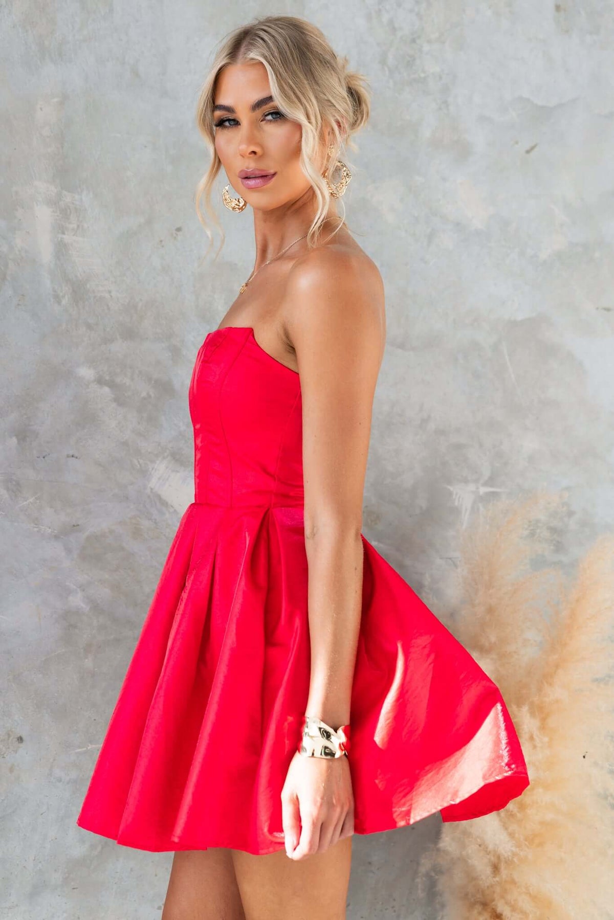 Model wearing the Aminah Dress, a strapless red satin dress with a flared skirt and tulle underlay.