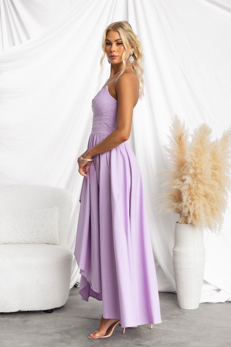Model in a strapless Kiss And Tell Maxi Dress, showcasing a lilac color, asymmetric hem, and elegant fit.